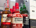 Assorted bourbon and whiskey bottles display with festive sweater decoration