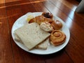Assorted breads for breakfast on white plate on wooden background Royalty Free Stock Photo