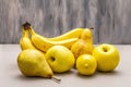 Assorted bright yellow fruits. Fresh banana, pear, apple, lemon. Harvest on a stone background Royalty Free Stock Photo