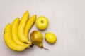 Assorted bright yellow fruits. Fresh banana, pear, apple, lemon. Harvest on a stone background