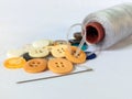 Assorted buttons with a needle and thread spool on a white surface Royalty Free Stock Photo