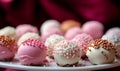 Assorted cake pops with elegant white and pink frosting and decorative sprinkles displayed against a blurred red background