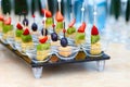 Assorted canapes of fruit and cheese on a glass platter on the background of glasses and champagne. Catering Royalty Free Stock Photo