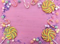 Assorted candy and lollipop on pink wood table.