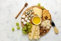 Assorted cheese platter with grapes, honey, and crackers on wooden board Royalty Free Stock Photo