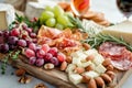 Assorted cheeses, meats, fresh fruits, nuts and appetizers beautifully arranged on a wooden board. Generative AI Royalty Free Stock Photo