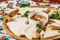 Assorted cheeses on round wooden board plate served with white wine Guda cheese, cheese grated bark of oak, hard cheese slices, Royalty Free Stock Photo