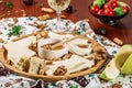 Assorted cheeses on round wooden board plate served with white wine Guda cheese, cheese grated bark of oak, hard cheese slices, Royalty Free Stock Photo