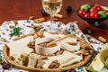 Assorted cheeses on round wooden board plate served with white wine Guda cheese, cheese grated bark of oak, hard cheese slices, Royalty Free Stock Photo