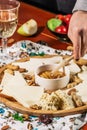 Assorted cheeses on round wooden board plate served with white wine Guda cheese, cheese grated bark of oak, hard cheese slices, Royalty Free Stock Photo