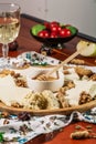 Assorted cheeses on round wooden board plate served with white wine Guda cheese, cheese grated bark of oak, hard cheese slices, Royalty Free Stock Photo