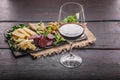 Assorted cheeses, sausages, smoked meat, lettuce, bread, olives, glass of red wine and on a dark flat plate of tuff on a dark Royalty Free Stock Photo