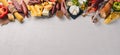 Assorted cheeses and traditional sausages and vegetables on a white wooden background. Royalty Free Stock Photo