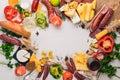 Assorted cheeses and traditional sausages and vegetables on a white wooden background. Royalty Free Stock Photo