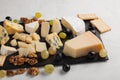 Assorted cheeses with white grapes, walnuts, crackers and on a stone Board. Food for a romantic date on a light background Royalty Free Stock Photo