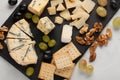 Assorted cheeses with white grapes, walnuts, crackers and on a stone Board. Food for a romantic date on a light background Royalty Free Stock Photo