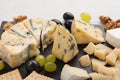 Assorted cheeses with white grapes, walnuts, crackers and on a stone Board. Food for a romantic date on a light background Royalty Free Stock Photo