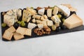 Assorted cheeses with white grapes, walnuts, crackers and on a stone Board. Food for a romantic date on a light background Royalty Free Stock Photo