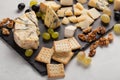 Assorted cheeses with white grapes, walnuts, crackers and on a stone Board. Food for a romantic date on a light background Royalty Free Stock Photo