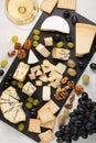 Assorted cheeses with white grapes, walnuts, crackers and white wine on a stone Board. Food for a romantic date on a light backgro Royalty Free Stock Photo