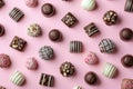 Assorted chocolate candies on pink background, top view. Chocolate pralines flat lay. Handmade chocolate candy sweets