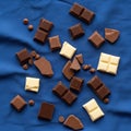 Assorted chocolate pieces and chips scattered on a blue fabric background Royalty Free Stock Photo