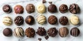 Assorted chocolate truffles arranged in rows on a marble background. World Chocolate Day