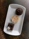 3 Assorted Chocolate Truffles On A White Dish With Wooden Table