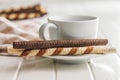 Assorted Chocolate and Vanilla Cream Filled Wafer rolls and coffee cup on white table Royalty Free Stock Photo
