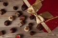 Assorted chocolates in elegant red gift pack with golden ribbon put on top of a wooden table.