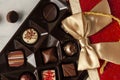 Assorted chocolates in elegant red gift pack with golden ribbon put on top of a wooden table.