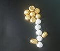 Assorted chocolates in gold and silver coloured foil top view arranged in flower shape.