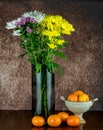 Assorted Chrysanthemum Flowers in a Glass Vase with Chalice Bowl and Satsuma Oranges on a Wooden Table Top Royalty Free Stock Photo
