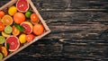 Assorted citrus fruit in a wooden box. Orange, tangerine, grapefruit, lemon. On a wooden background. Royalty Free Stock Photo