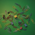 Assorted colored paperclips and binder clips are scattered across a green surface. Royalty Free Stock Photo