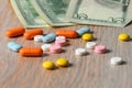 Assorted colored pills and money on the table. The concept of buying pills. The concept of increasing the price of tablets