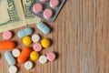 Assorted colored pills and money on the table. The concept of buying pills. The concept of increasing the price of tablets