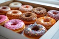 Assorted colorful donuts in an open box, a tempting selection of different flavors