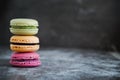 Assorted colorful french macaroons on a dark stone background