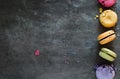 Assorted colorful french macaroons on a dark stone background