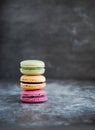 Assorted colorful french macaroons on a dark stone background