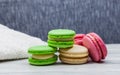 Assorted colorful macaroons on a wooden table and blue background, next to a white towel Royalty Free Stock Photo