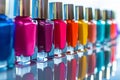 Assorted colorful nail polish bottles in a row with reflections on glass surface Royalty Free Stock Photo