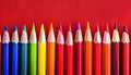 Assorted colorful pencils aligned on bold crimson surface for artistic endeavors Royalty Free Stock Photo