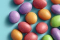 Multicolored speckled Easter eggs scattered on blue background surface. Themed candy by color. Concept of Easter celebration Royalty Free Stock Photo