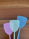 Assorted coloured fly swatters against a wooden background Royalty Free Stock Photo