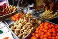 Assorted deep fried street food sold at a food cart along a sidewalk