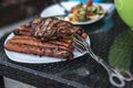 Assorted delicious grilled meat with salad in background white plate on table for family bbq party