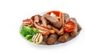 Assorted delicious grilled meat and sausages with tomatoes and bbq sauce on white plate isolated on blue background. Royalty Free Stock Photo