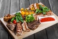 Assorted delicious grilled meat and vegetables with fresh salad and bbq sauce on cutting board Royalty Free Stock Photo